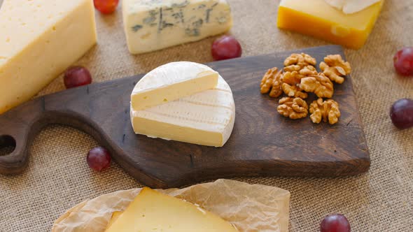 Cheese Platter with Nuts and Grapes on a Wooden Cutting Board