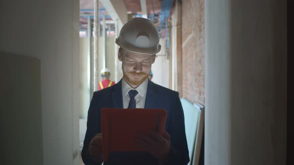 Architect Wearing Hardhat Holding Digital Tablet on Construction Site