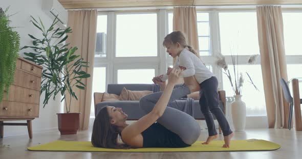 Happy Beautiful Family Healthy Young Mom Lifting Cute Little Child Daughter Up Playing Plane on Wall