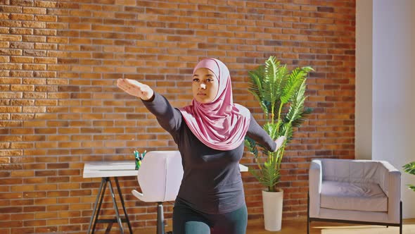 Young Muslim Woman in a Headscarf is Doing Yoga Asanas at Home