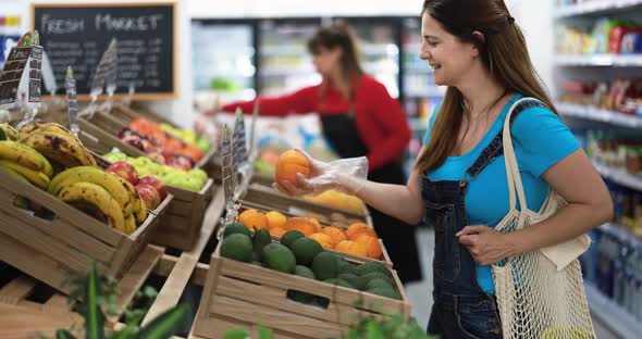 Female customer buying organic fruits inside eco fresh market