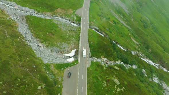 aerial of Caravan driving on mountain road with waterfall, Switzerland