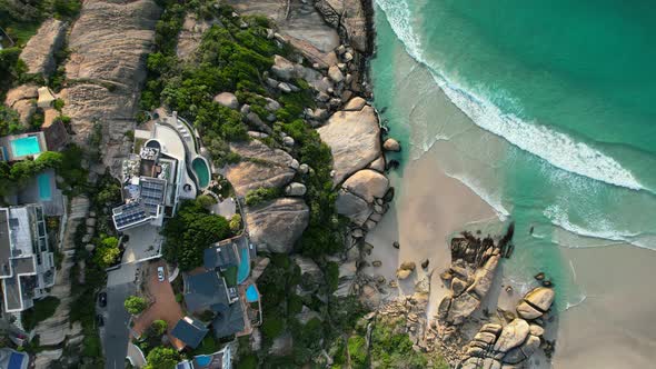 oceanfront homes at Llandudno Beach coastline at sunset in Cape Town, aerial