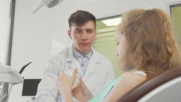 Professional Dentist Talking To His Young Patient Explaining Dental Care