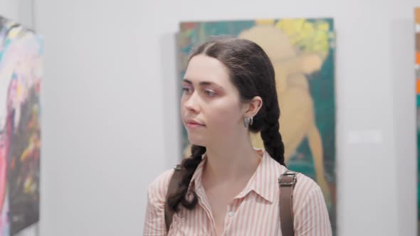 Portrait of young caucasian woman walking and contemplating at the artwork