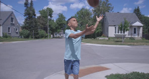 Young boy drops his football while walking down the street