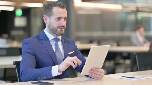 Successful Middle Aged Businessman Celebrating on Tablet at Work