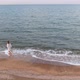 A Happy Girl in a Wet Shirt Runs Along a Sandy Beach and the Seashore - VideoHive Item for Sale