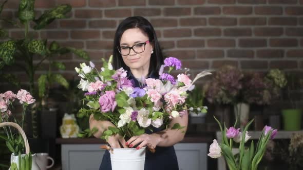 florist girl  with glasses in workplace puts creative bouquet in decorated vase