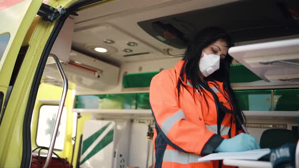 Young Female Paramedic Fills Documents Inside Ambulance Vehicle