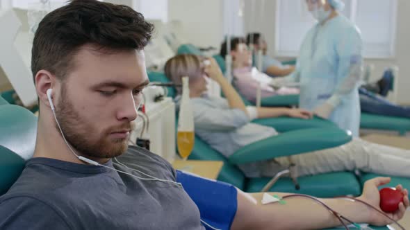 Man Listening to Music with Headphones During Giving Blood