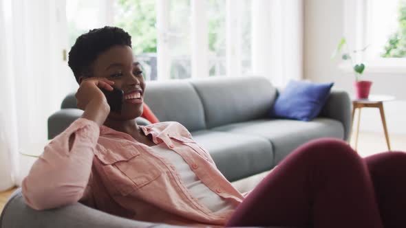 African american woman talking on smartphone while sitting on the couch at home