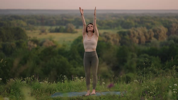 Slow Motion Young Woman in Tracksuit Practices Yoga Position in the Mountains