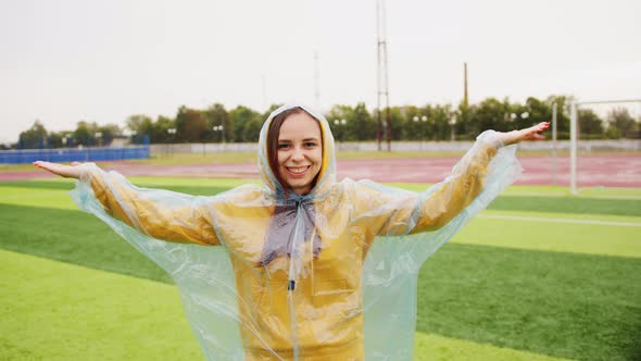 Young Woman in Raincoat on Sports Field in Rain