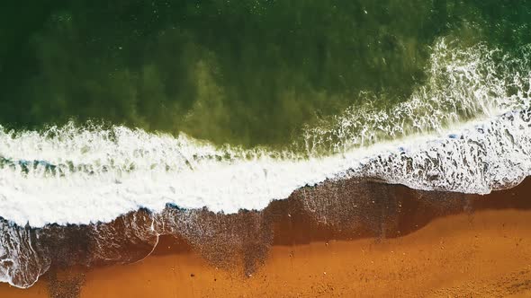 AERIAL: Waves crash on beach in Barcelona, Spain. Shot from above with a drone