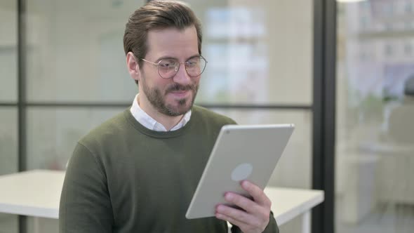 Online Video Chat on Tablet By Young Businessman in Office