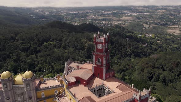 Brightly coloured red and yellow towers of Pena Palace, Sintra, against Natural Park forest.