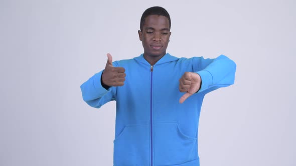 Young Confused African Man Choosing Between Thumbs Up and Thumbs Down