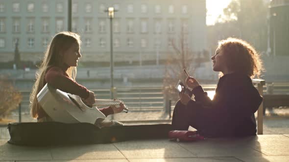 Teenage Girls Sitting on the City Embankment