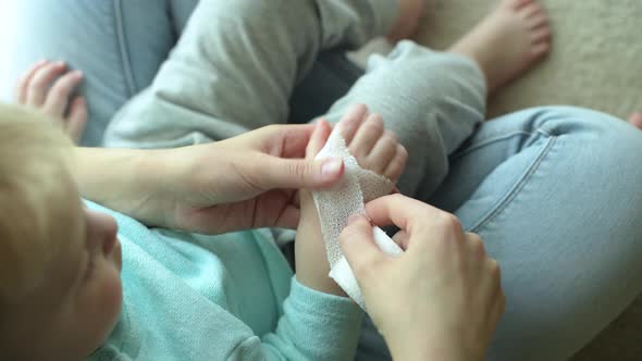 A woman heals the hand of baby, bandaging it with a bandage