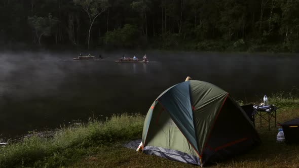 Tent Folding Table and Camping Gear on Fog Lake Shore in Early Morning Forest