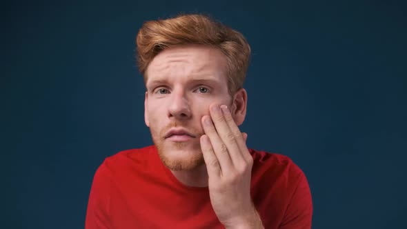 Face Close Up of a Young Ginger Man Looking at His Skin Problems Examining His Face Over Dark Blue