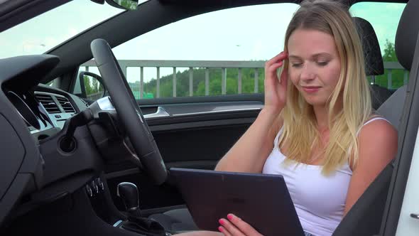 A Young Beautiful Woman Sits Relaxed in a Luxurious Car and Works on a Tablet - Closeup