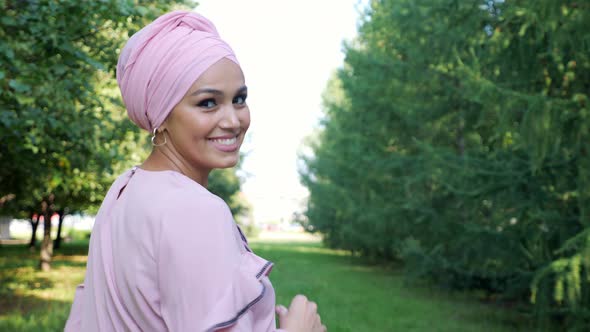 Beautiful Muslim Woman in Closed Clothes Runs Among the Trees and Smiles