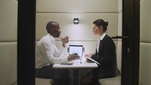 African Businessman and a Female Financier Discuss Financial Work Matters While Sitting in the