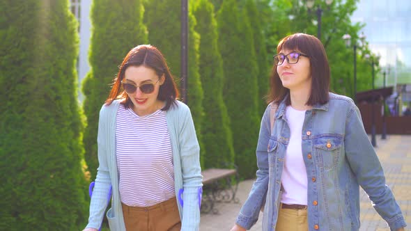 a Young Disabled Woman with an Injury on Crutches Goes with a Friend and Talk Smiling