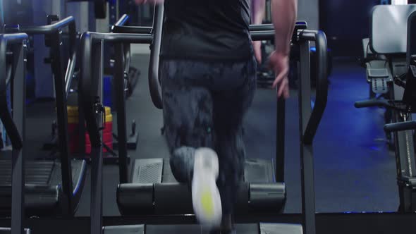 A Sporty Man Runs on a Treadmill in the Gym in Front of a Mirror