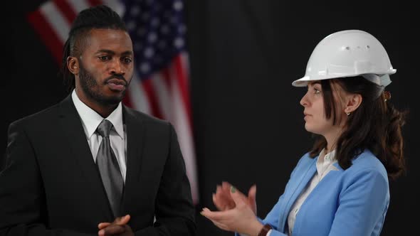 Confident Caucasian Woman in Hard Hat Yielding the Floor to African American Man in Suit