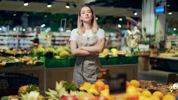portrait of saleswoman, woman smiling and looking at camera in supermarket. 