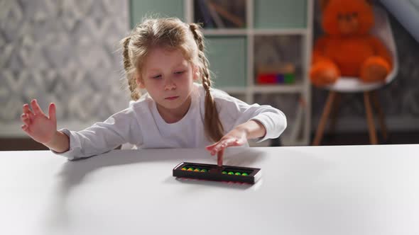 Little Child Plays with Abacus Sitting at Desk at Maths