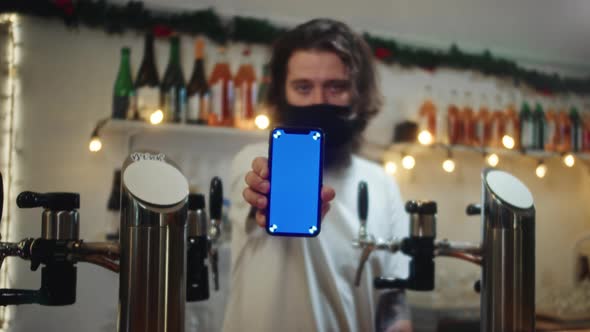 Barman in Mask Showing Blue Screen on Phone