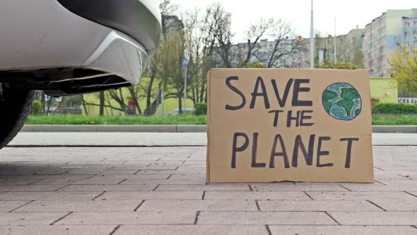 SAVE THE PLANET Poster Next to the Exhaust Pipe of a Car