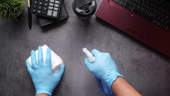 Hand in Blue Rubber Gloves Holding Spray Bottle Cleaning Table