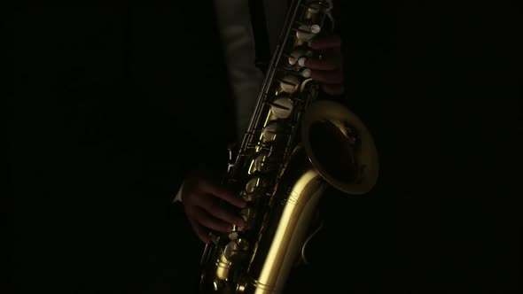 Musician Plays Saxophone in Dark and is Illuminated By the Light in Studio