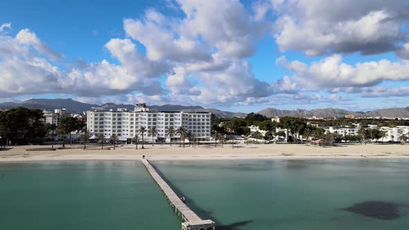 Flying Downwards towards The Blue Sea With Clouds and Mountains In the Background behind a Wooden Pi