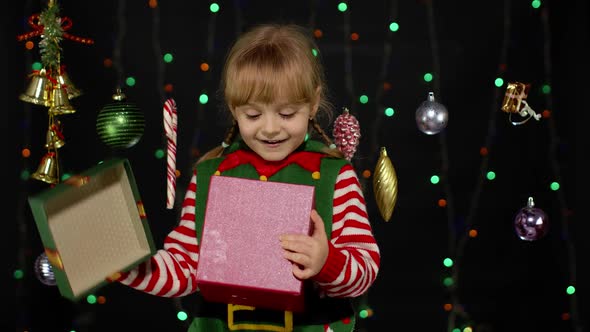Kid Girl in Christmas Elf Santa Helper Costume with Present Gift Box Looking Inside
