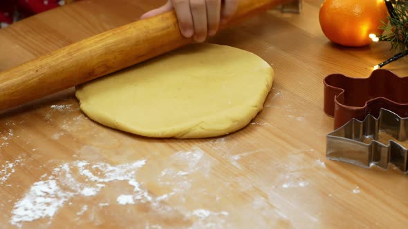 A little girl rolls out an adze for making Christmas dessert. Christmas gingerbread and cookies.