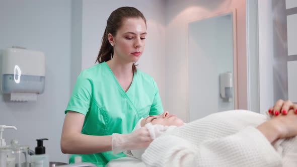 Female Beautician Makes Face Rejuvenation and Cleansing Procedure for Girl