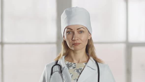 The lady doctor nods disapprovingly at the camera. Professional female doctor in uniform with a phon