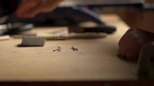 Caucasian man placing tools on a wooden table, preparing to work with wood using nails, hammers, pli