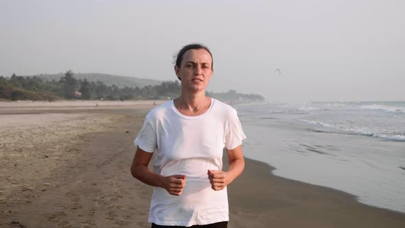 Woman with Bandage on Injured Knee Is Running on the Sandy Beach.