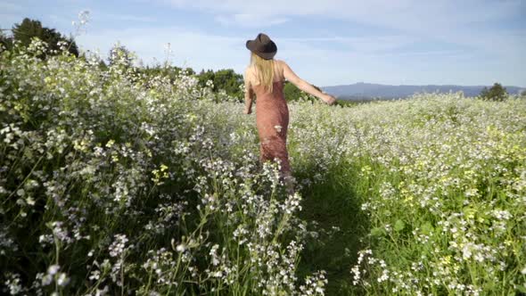 SLOMO of Young Woman Skipping Through a Field of Flowers