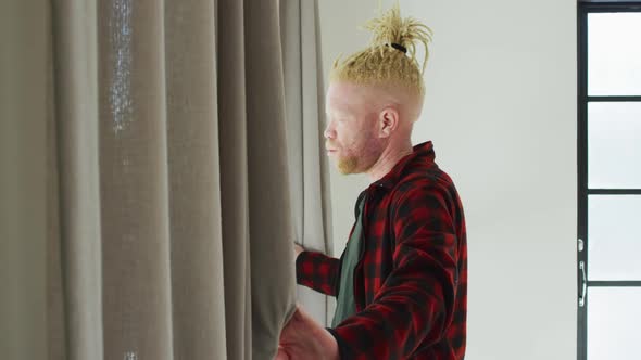 Thoughtful albino african american man with dreadlocks looking at the window