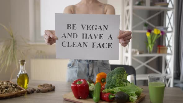 Front View Unrecognizable Woman Showing Be Vegan and Have a Clean Face Standing Indoors