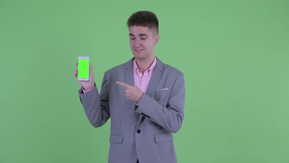 Happy Young Businessman Showing Phone and Giving Thumbs Up
