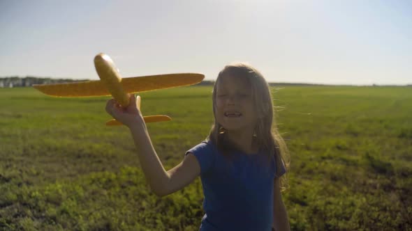 Little Girl Child In A Field With A Toy Plane At Sunset